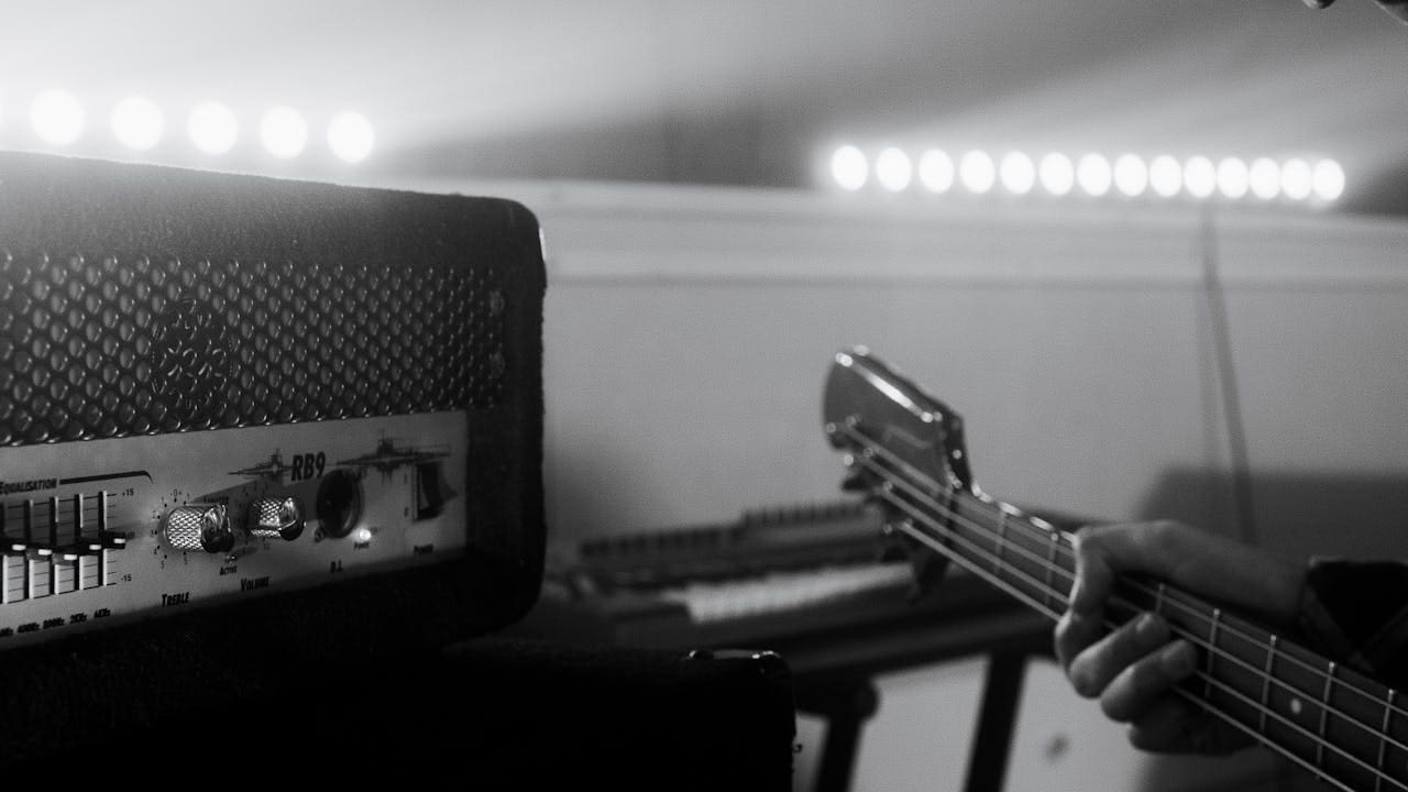 Black and white close-up of bass guitar with amplifier, capturing musical vibe in studio.